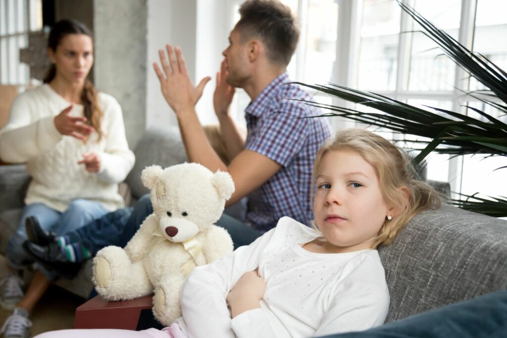 enfant sur le canapé a coté de ses parents qui se querelle, montrant la situation familiale avec un manipulateur et l'impact sur l'enfant