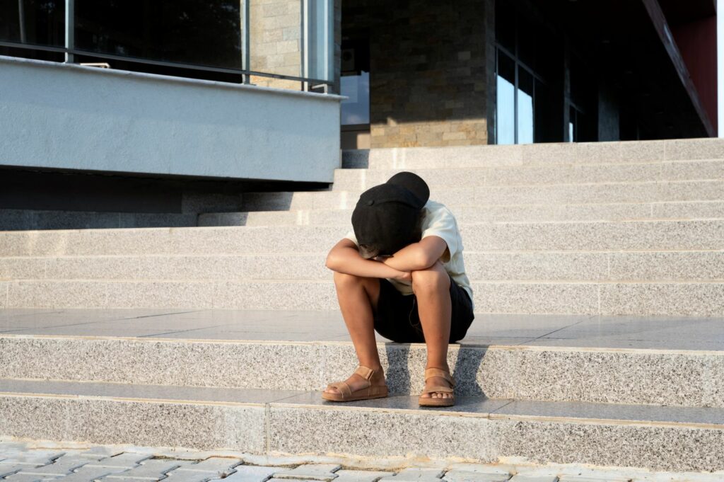 enfant assis sur une marche d'escalier en train de pleurer marquant une peur de l'abandon