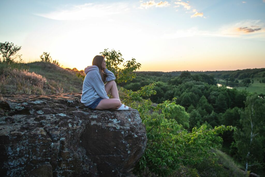 jeune femme assise sur une falaise regardant l'horizon pouvant être associer à la solitude affective