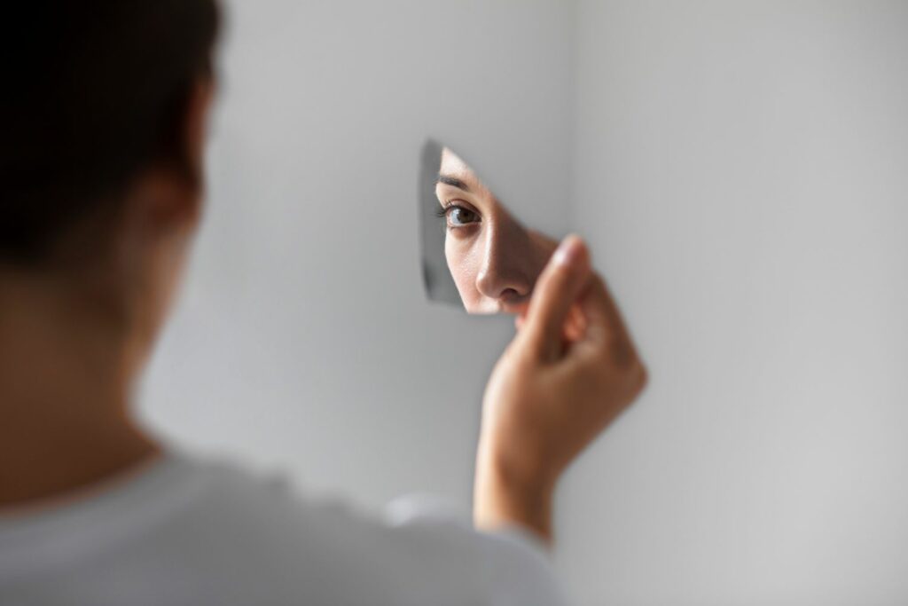 portrait d'une femme qui se regarde dans un miroir cassé montrant l'impact d'être tout le temps dans le contrôle