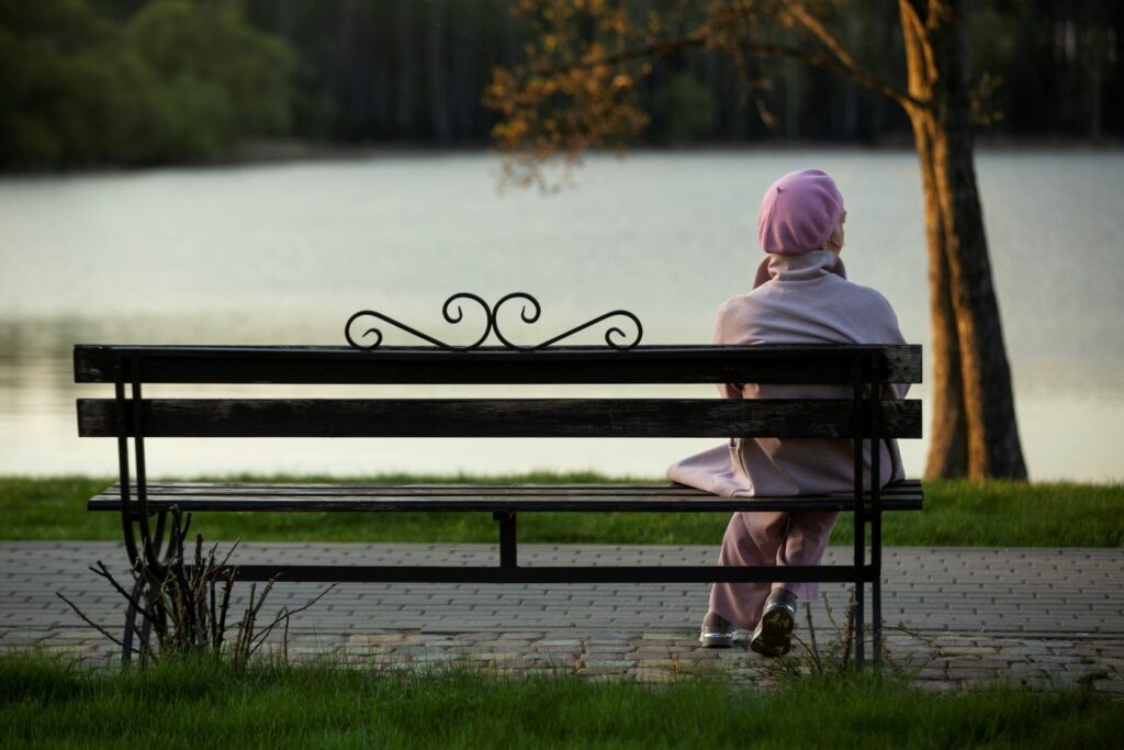 jeune femme habille en rose assise seule sur un banc faisant référence au sentiment d'abandon